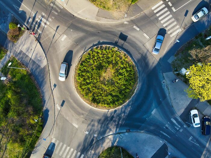 Aerial view of a roundabout with cars and pedestrians, illustrating bizarre facts about countries from locals.