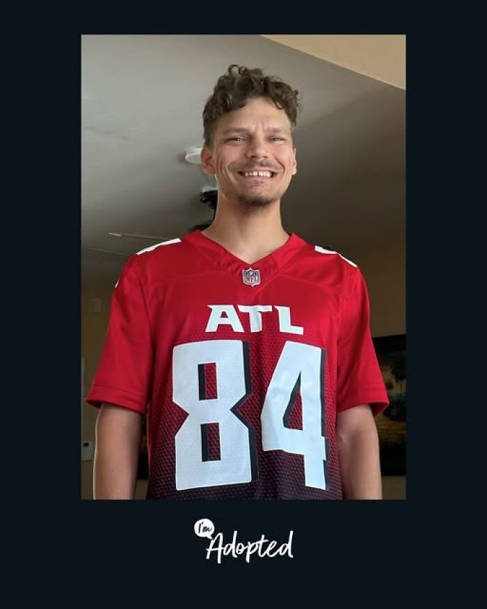 Smiling young man wearing a red ATL football jersey, representing inspiring adoption stories and journeys.