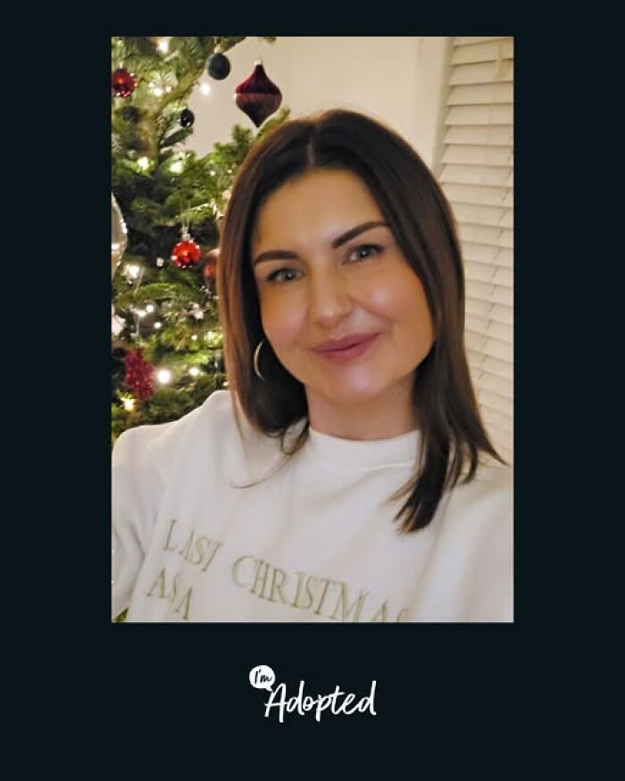 Smiling woman near decorated Christmas tree, representing wholesome and amazing adoption stories celebration.
