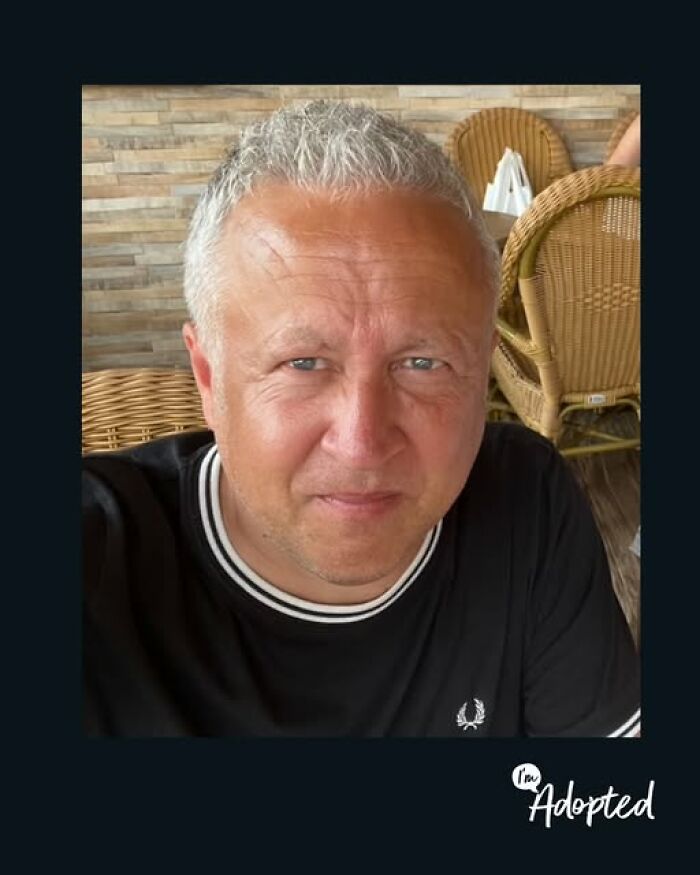Smiling middle-aged man sitting in a wicker chair, representing wholesome and amazing adoption stories.