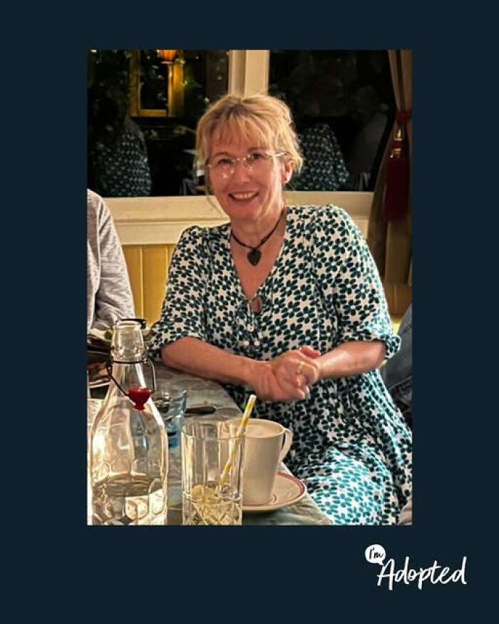 Smiling woman sitting at a table with drinks, representing wholesome and amazing adoption stories in a cozy setting.