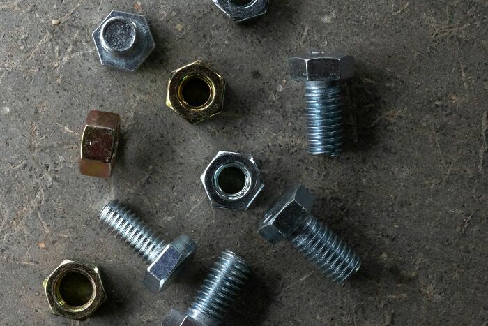Several metal bolts and nuts scattered on a rough surface, illustrating messed up school incidents. - 26