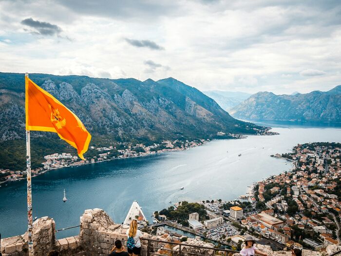 Scenic view of a coastal town with mountains and an orange flag, illustrating bizarre facts about countries.