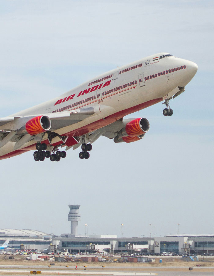 Air India airplane taking off from airport runway with landing gear extended during clear day flight