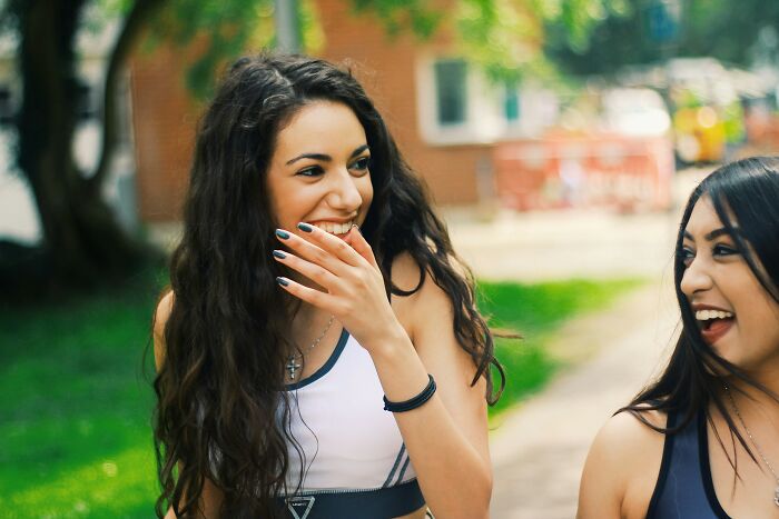 Two young women laughing outdoors, representing students with truly outrageous student names shared by a teacher.