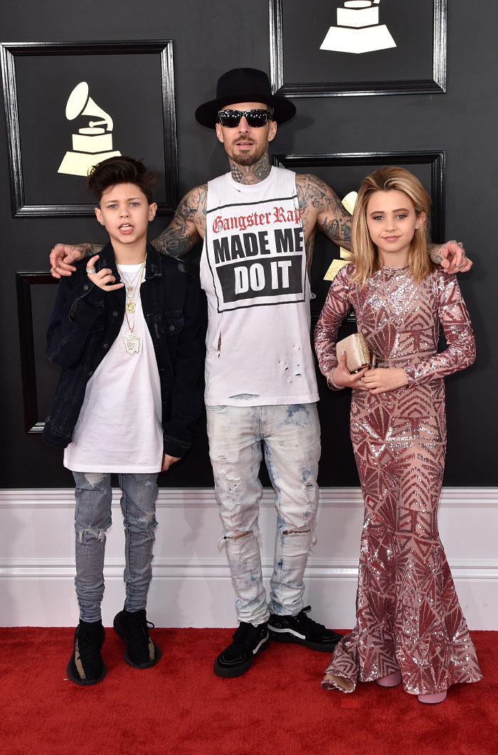 Man and two children posing on a red carpet event, highlighting Alabama Barker&rsquo;s net worth backed by generations of fame.