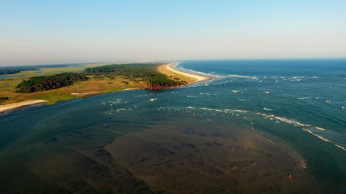 Aerial view of a coastline with forest and ocean waves, illustrating environmental risks on the brink of collapse. - 8