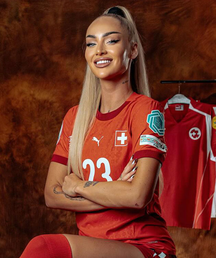 Female footballer in red Switzerland jersey with number 23, smiling confidently, showcasing her transformation and style.