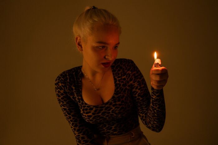 Young woman in a leopard print top holding a lighter flame, illustrating the pettiest things in breakups concept.