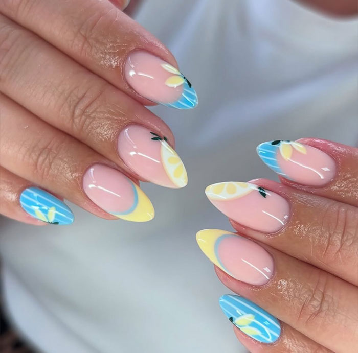 Almond nails with pastel yellow and blue citrus fruit designs showcasing trendy nail art for 2025 styles.