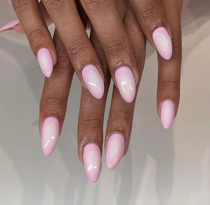 Hands with glossy pink ombre almond nails showcasing one of the top almond nails trends for 2025.