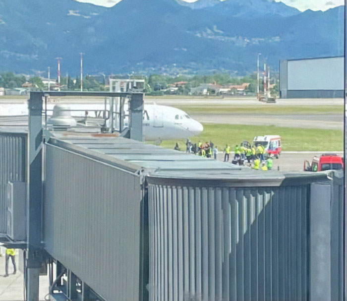 Airport scene with emergency responders near plane engine, related to man sucked into plane engine incident.