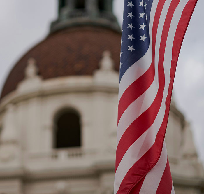 American flag waving in front of a historic building symbolizing a man threatening to explode plane mid-flight incident.