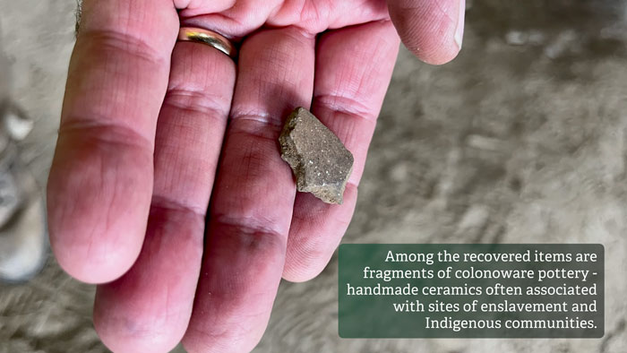 Hand holding a fragment of colonoware pottery found in a forgotten cellar packed with mysterious artifacts beneath historic US school.