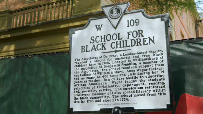 Historic US school sign for Black children, related to archaeologists discovering cellar with mysterious artifacts beneath site.