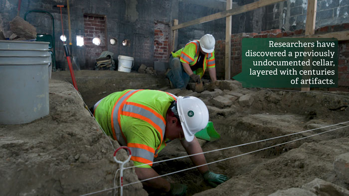 Archaeologists excavating a forgotten cellar beneath a historic US school, uncovering mysterious artifacts in layers.
