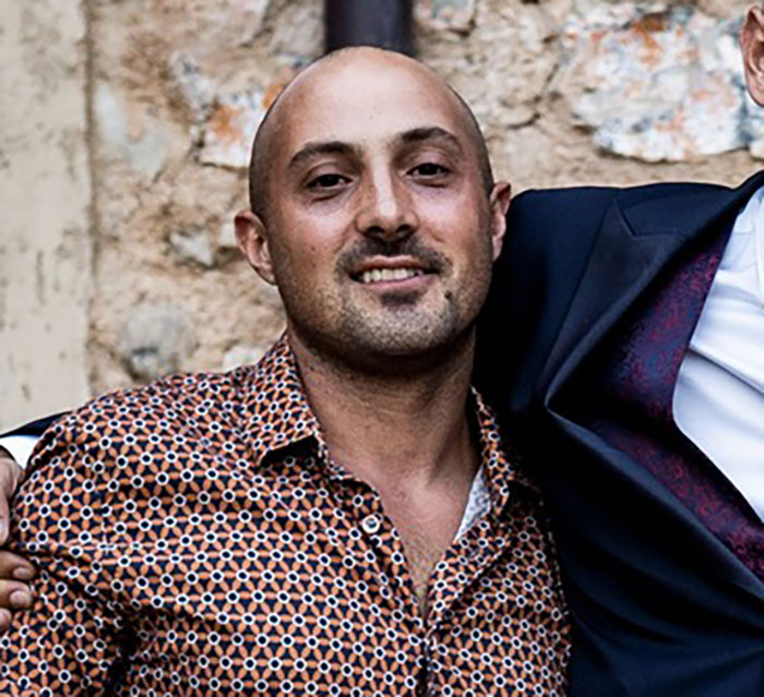 Man with a patterned shirt, identified as the man sucked into plane engine, posing with another person outdoors.