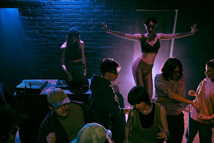 A group of people in a dimly lit room with a DJ, illustrating unusual private investigator cases. - 9