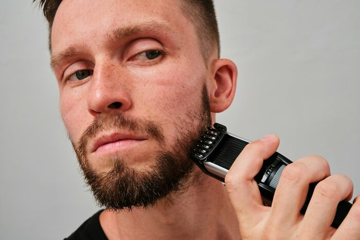 Man trimming beard with electric trimmer close-up, illustrating unusual items found on patients that made medical professionals gasp