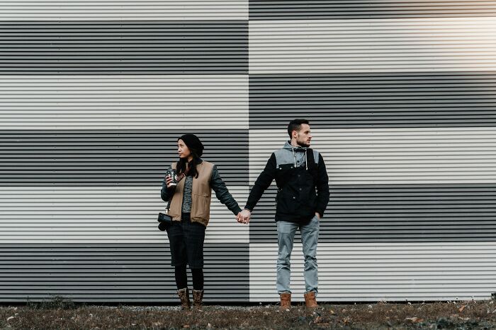 Couple holding hands but facing away from each other, illustrating married people who wish they were single and unhappy.