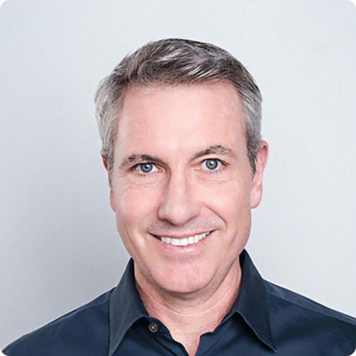 Middle-aged man with gray hair smiling, wearing a dark shirt, representing the wife of CEO accused of cheating scandal