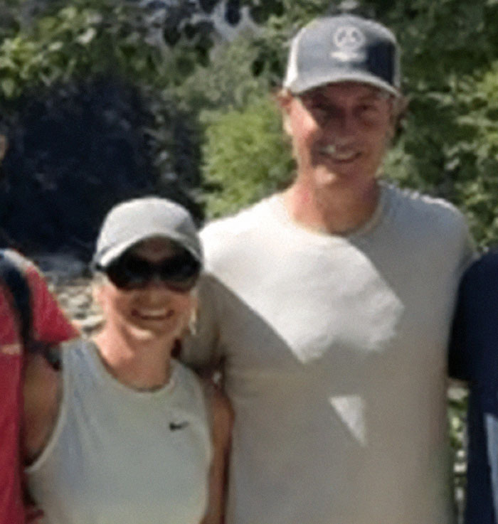 Couple outdoors wearing casual clothes and hats, related to wife of CEO accused of cheating at Coldplay concert.