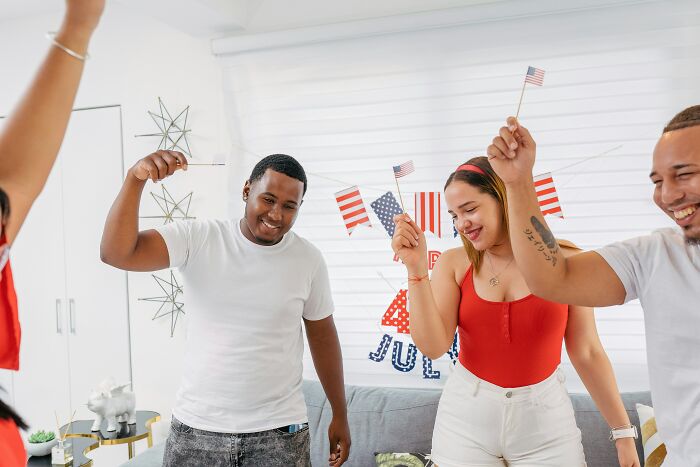 Group of travelers celebrating with small American flags indoors, sharing surprising things about the U.S. visit experience.