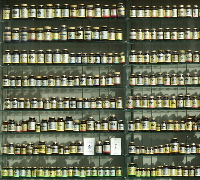 Glass shelves filled with numerous vintage medicine bottles representing bizarre beliefs people still fall for despite science. - 14