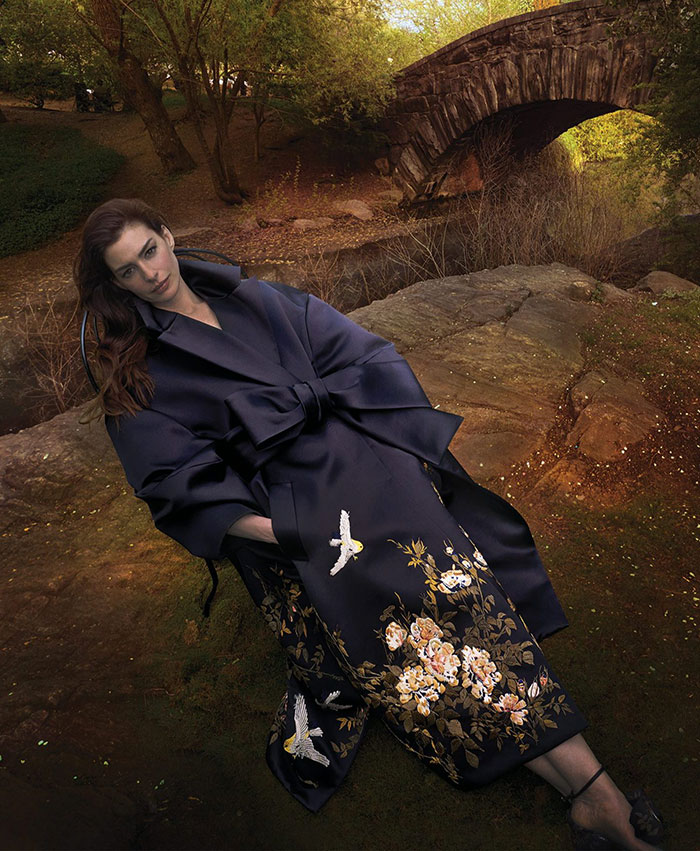 Anne Hathaway posing in a dark floral embroidered coat in an autumn outdoor setting for Vogue photoshoot. Anne Hathaway posing in a dark floral embroidered coat in an autumn outdoor setting for Vogue photoshoot.