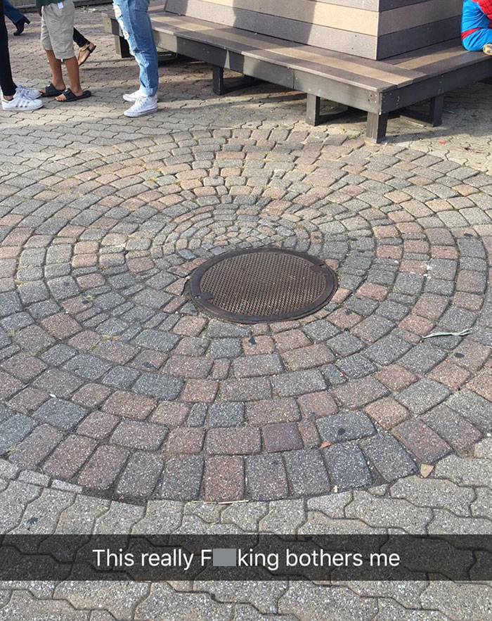 Uneven manhole cover disrupting the circular pattern of bricks, illustrating imperfect things that annoy people with OCD.