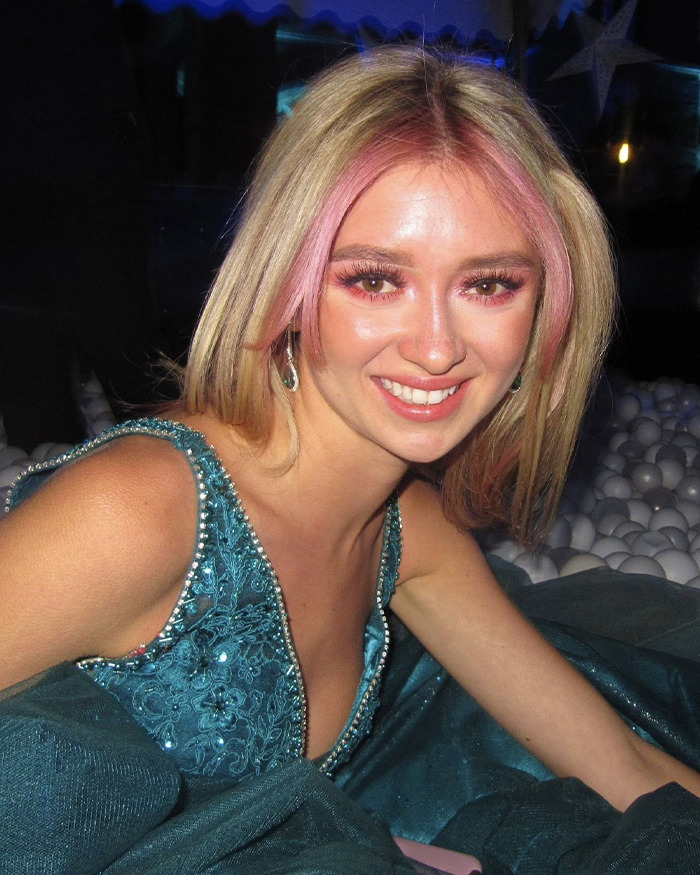 Young woman with pink highlights smiling in a blue dress, related to anti-vax refusal of chemotherapy and family dispute.