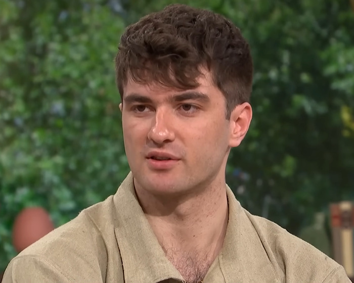 Young man discussing anti-vax woman&rsquo;s refusal of chemotherapy and family conflict in an indoor interview setting.