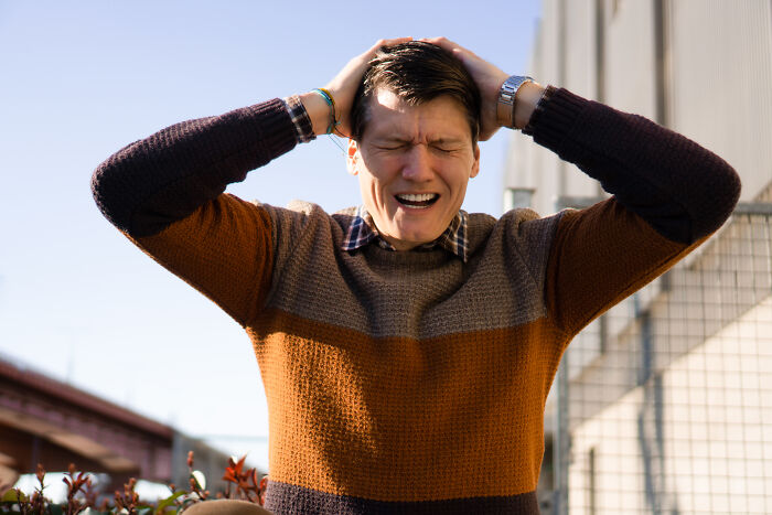 Young man outside holding his head in frustration, representing messed up school incidents memory. - 21