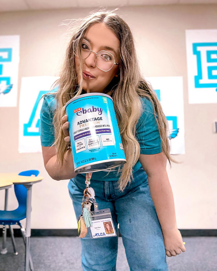 Young woman creatively drinking from a baby formula container in a casual indoor setting, showcasing unique sippers.