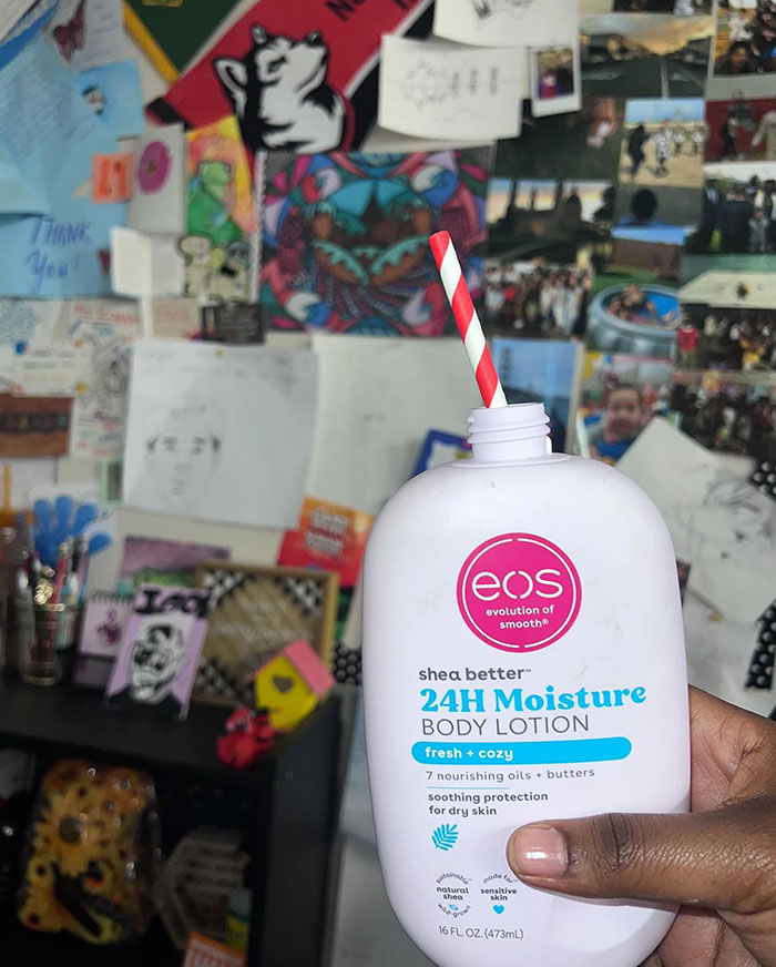 Hand holding a lotion bottle with a red and white striped straw as a creative sipper alternative to a cup.