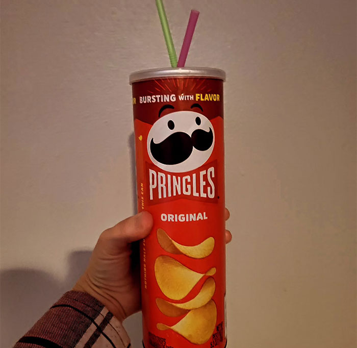 Hand holding a Pringles can with straws inserted, showcasing creative sippers choosing to drink from anything but a cup.