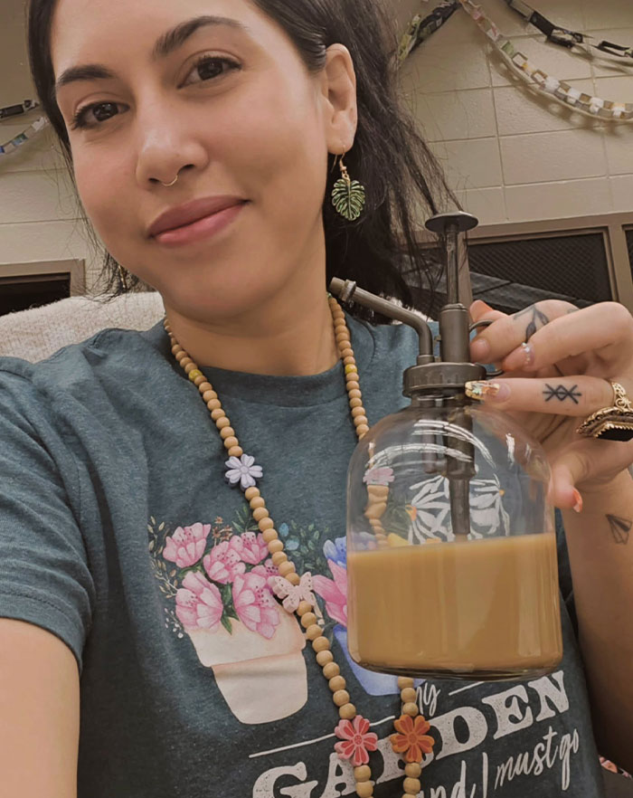 Woman drinking from a creative sipper made from a vintage glass pump container, showcasing unique drinking alternatives.