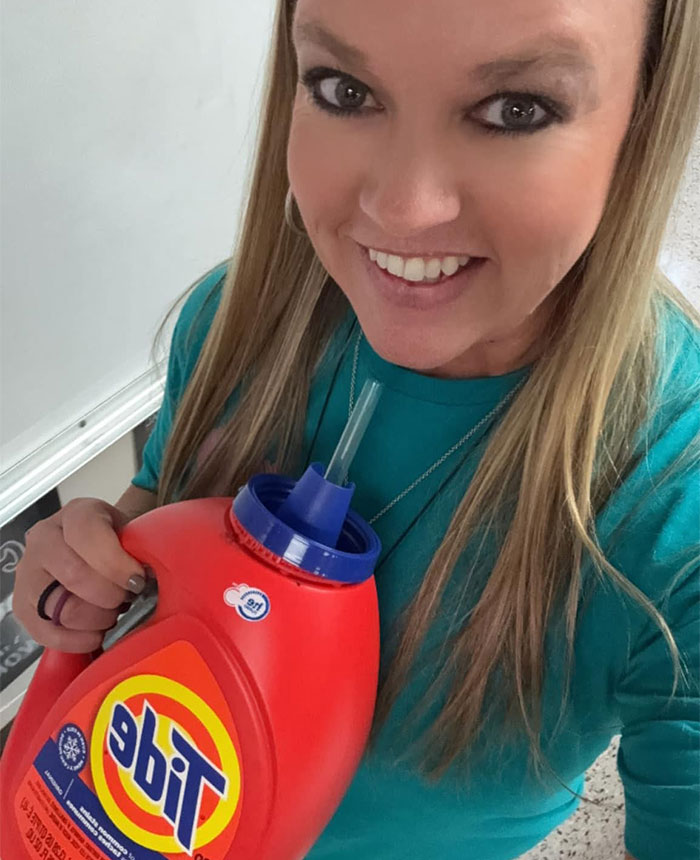 Woman smiling and drinking from a Tide detergent bottle using a straw showing creative non-cup sippers.