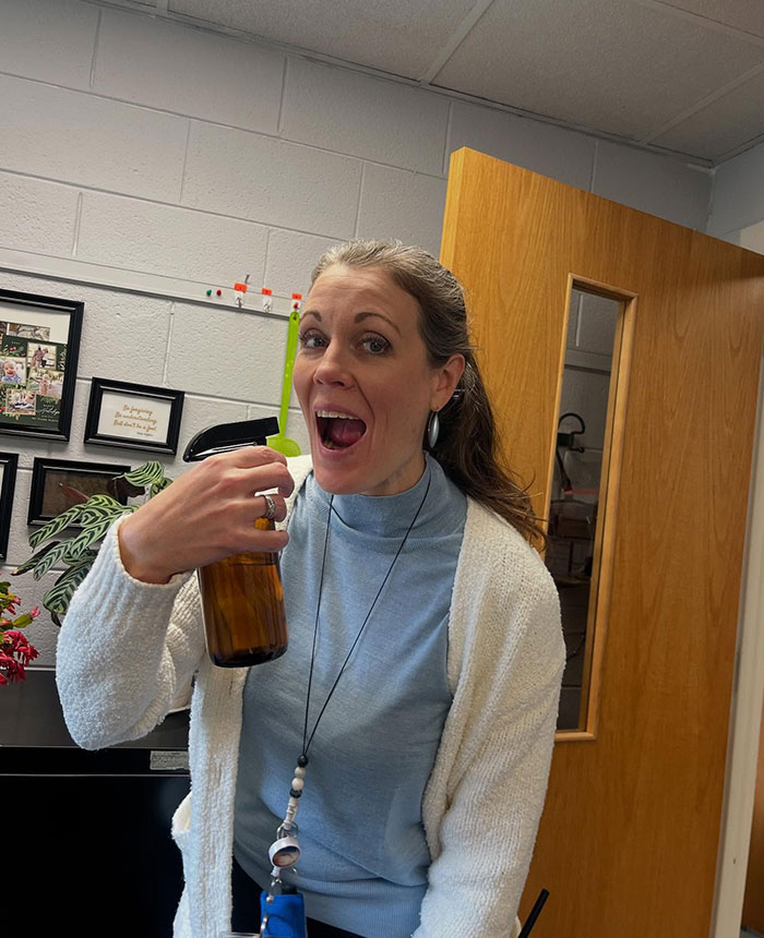 Woman sipping from a brown bottle with a green straw, showcasing creative sippers who drink from anything but a cup.
