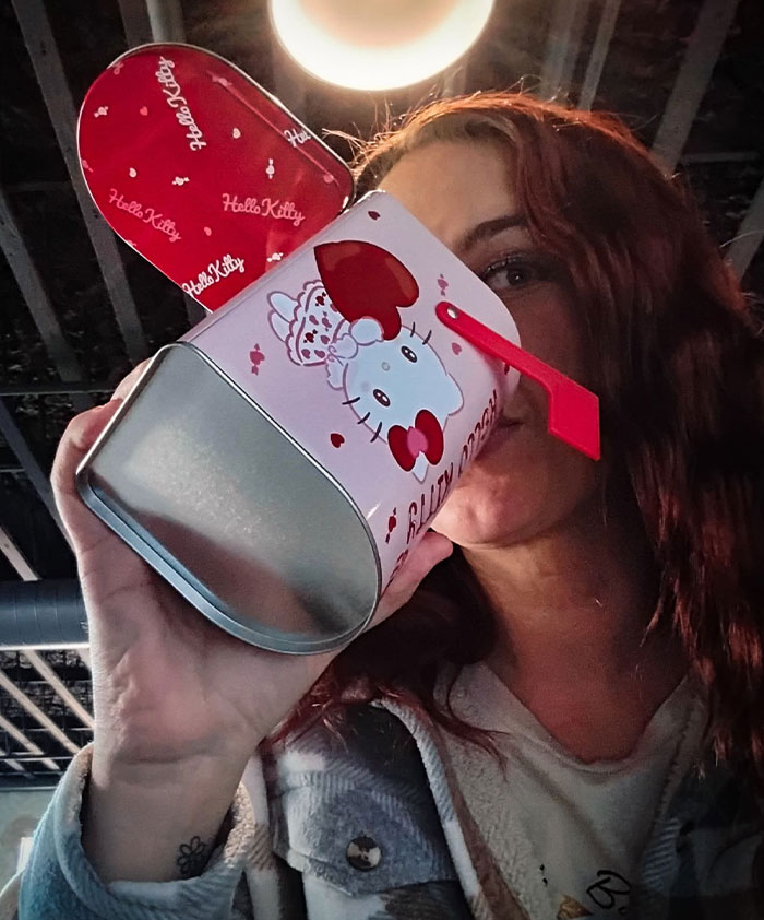 Woman creatively sipping from a Hello Kitty-themed mailbox, showcasing unique sippers who use anything but a cup.