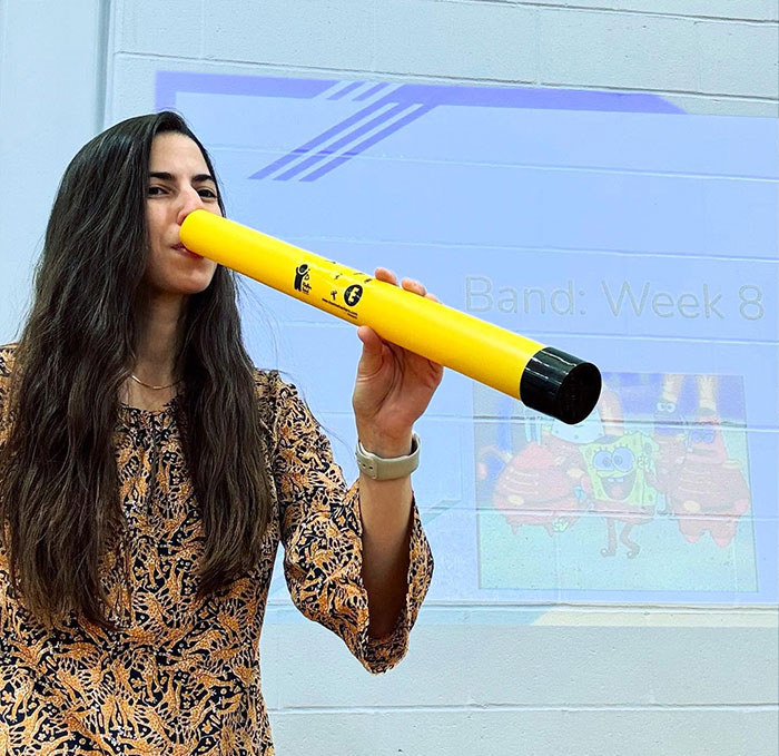 Woman sips from a creative oversized yellow object, showcasing unique drinking ideas beyond traditional cups.