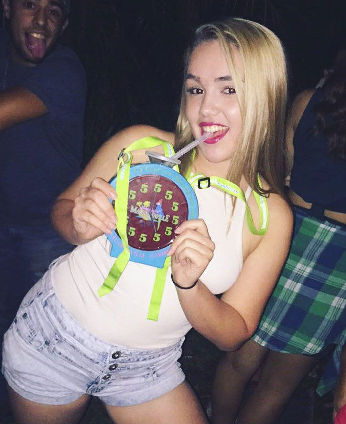 Young woman sipping through a straw from an unusual container at a party, showcasing creative sippers drinking from anything but a cup.