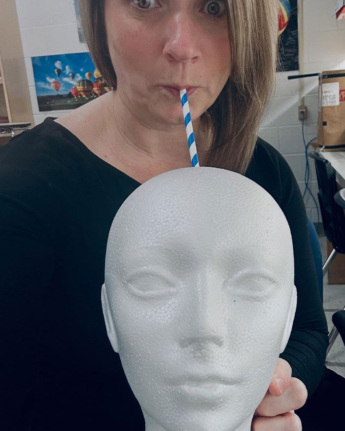 Woman using a striped straw to sip from a foam mannequin head in a creative alternative sipper idea.