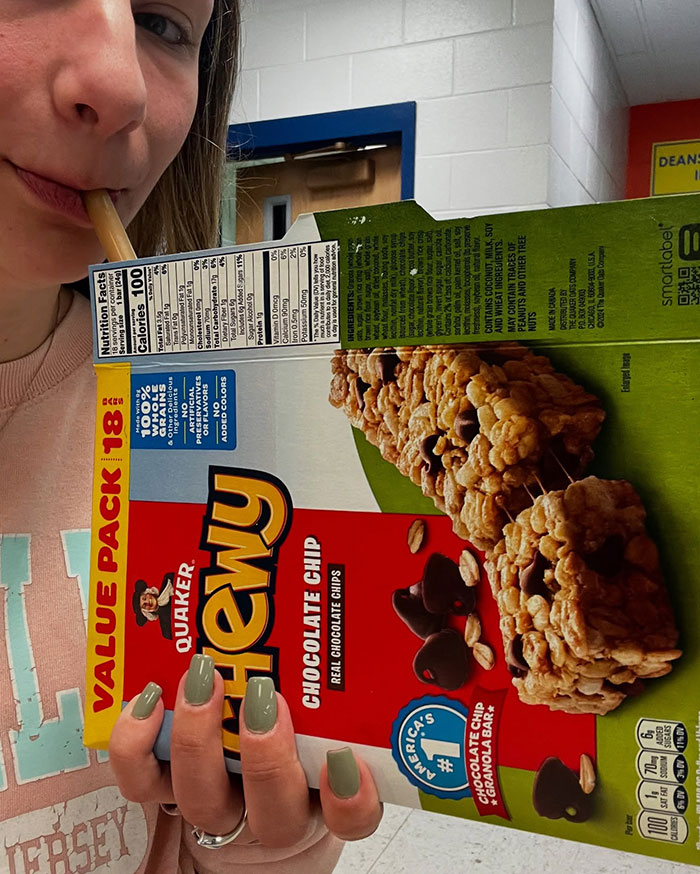 Person creatively sipping through a straw inserted in a granola bar box instead of using a cup.