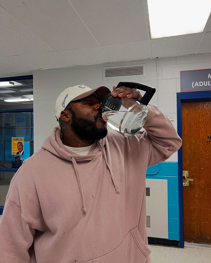 Man drinking water from a coffee pot, showcasing creative sippers choosing to drink from anything but a cup indoors.