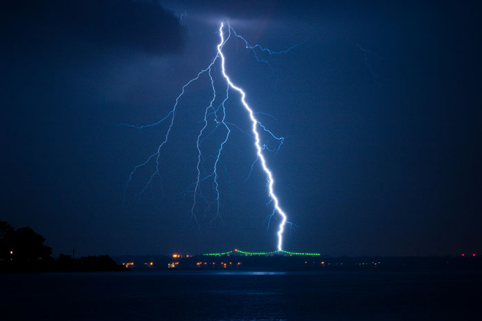 Lightning strike over a dark lake at night symbolizing the tragic death of Olympic medalist skier in a storm. - 2