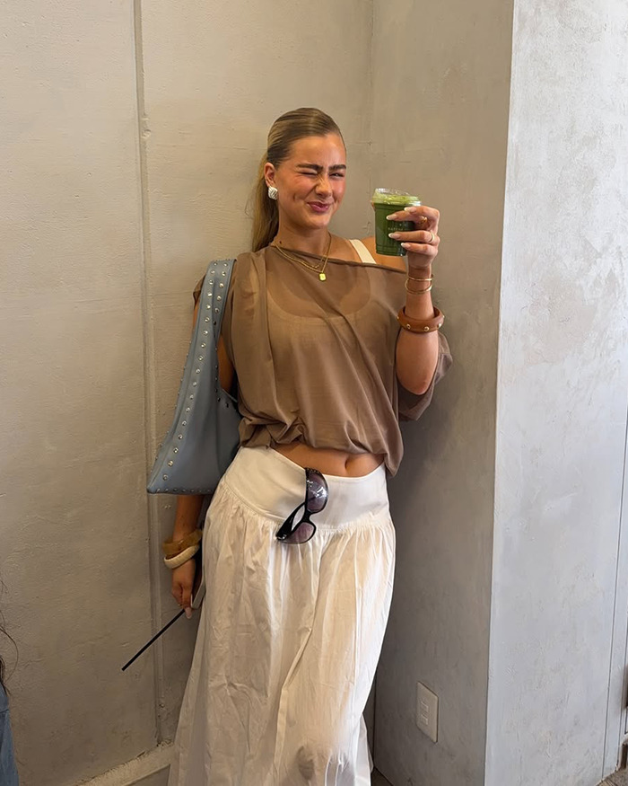 Australian influencer with a casual outfit holding a green drink, accused of tone deaf posts during Japan trip controversy. - 4