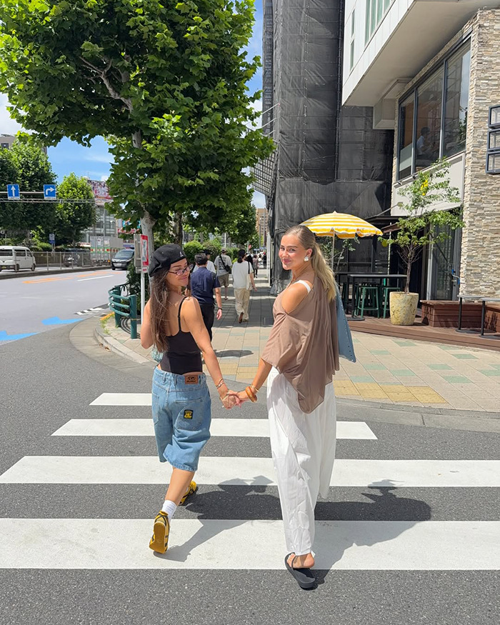 Two women holding hands crossing a street in Japan, capturing Australian influencer during Japan trip on a sunny day. - 6
