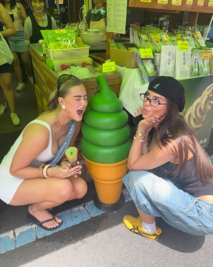 Two young women posing with a large green ice cream cone outside a market during an Australian influencer Japan trip. - 7