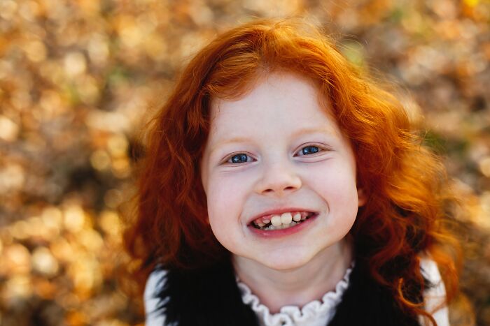 Smiling red-haired child outdoors in autumn, illustrating harmless lies parents told that left kids low key traumatized. - 27